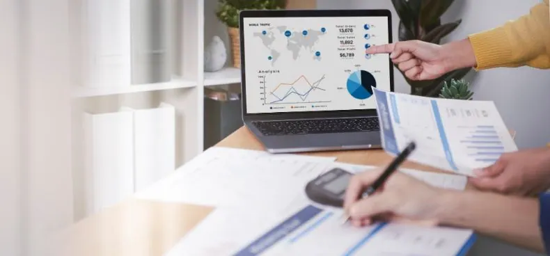 Duas pessoas analisando gráficos e dados de RH em um notebook e papéis.