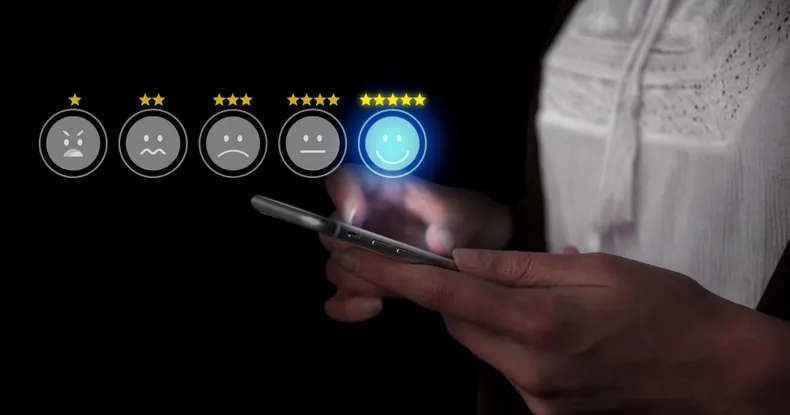 Mãos segurando um celular, com ícones de avaliação de satisfação acima.