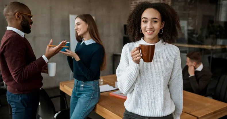 Quatro colegas de trabalho conversando e sorrindo em um escritório.