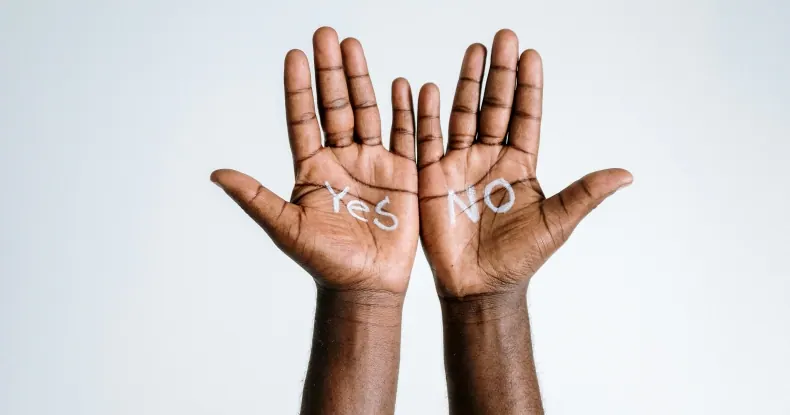 Duas mãos escuras com as palmas abertas, uma com Yes e outra com No.