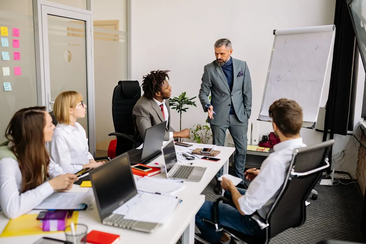 Líder experiente em reunião com equipe diversa, discutindo ideias.