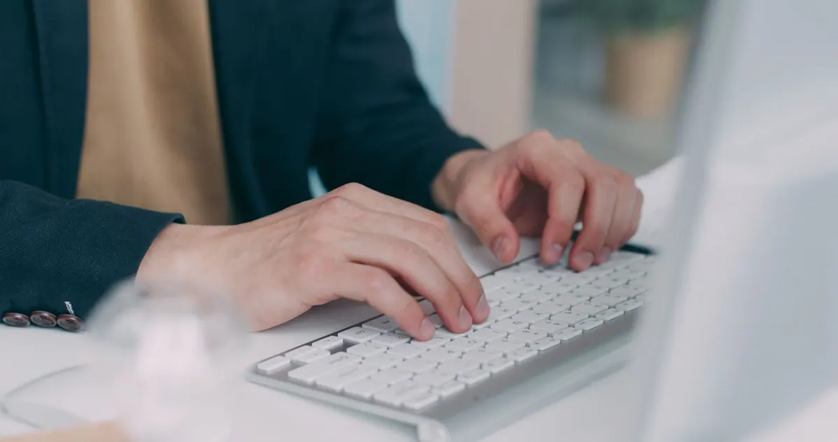 Mãos profissionais digitando em um teclado branco, focando no desenvolvimento de carreira.