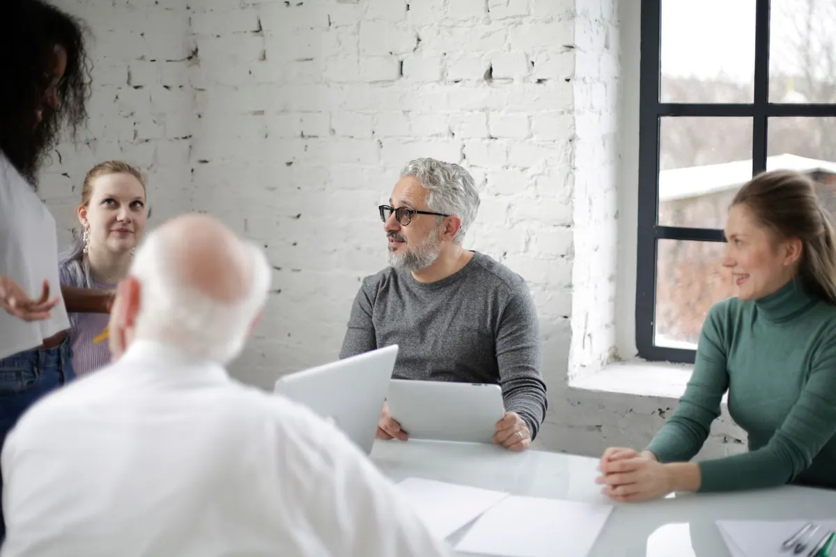 Pessoas de diferentes idades em uma reunião de trabalho, construindo pontes entre gerações.