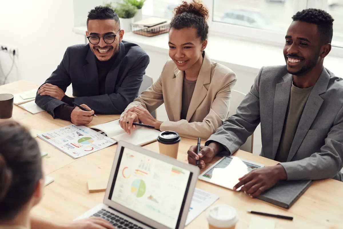 Pessoas sorrindo em uma reunião de trabalho, transmitindo um ambiente saudável.