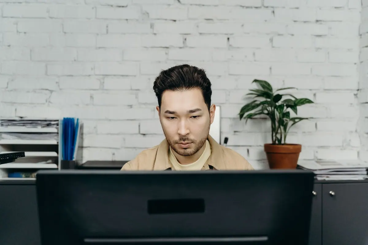 Homem focado trabalhando em um computador em um escritório moderno.