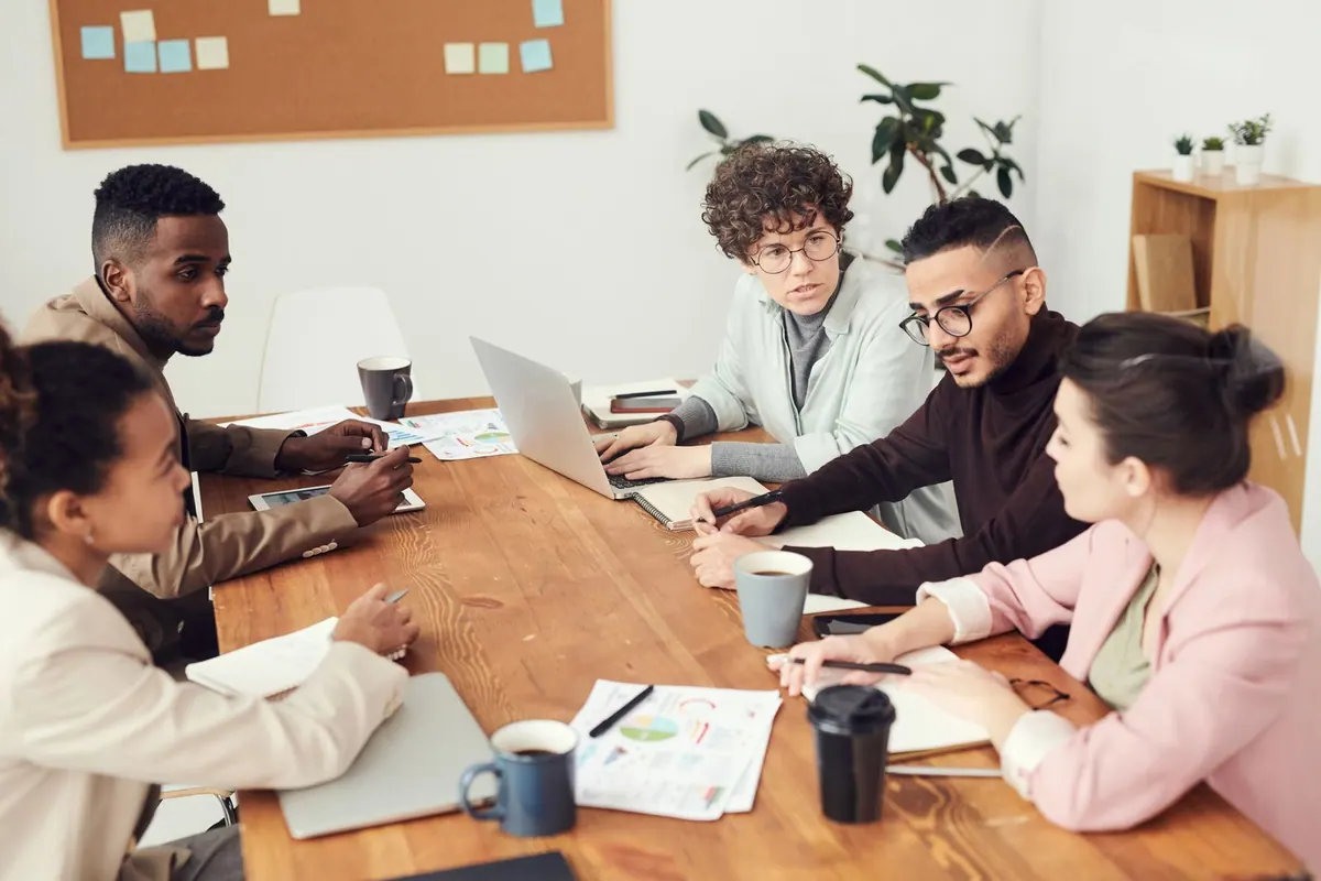 Pessoas de diferentes gerações discutindo ideias em uma mesa de reunião.