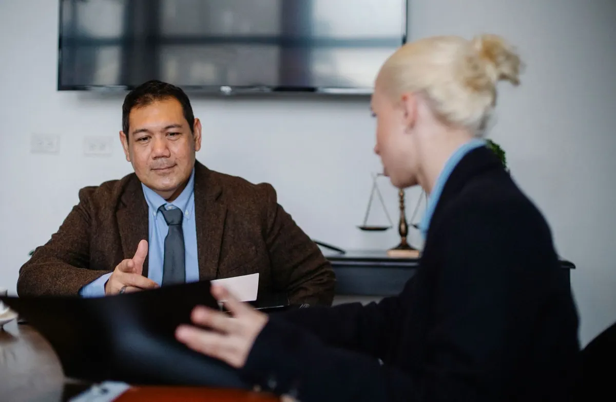 Dois colegas de trabalho multiétnicos concentrados discutindo negócios em um escritório.
