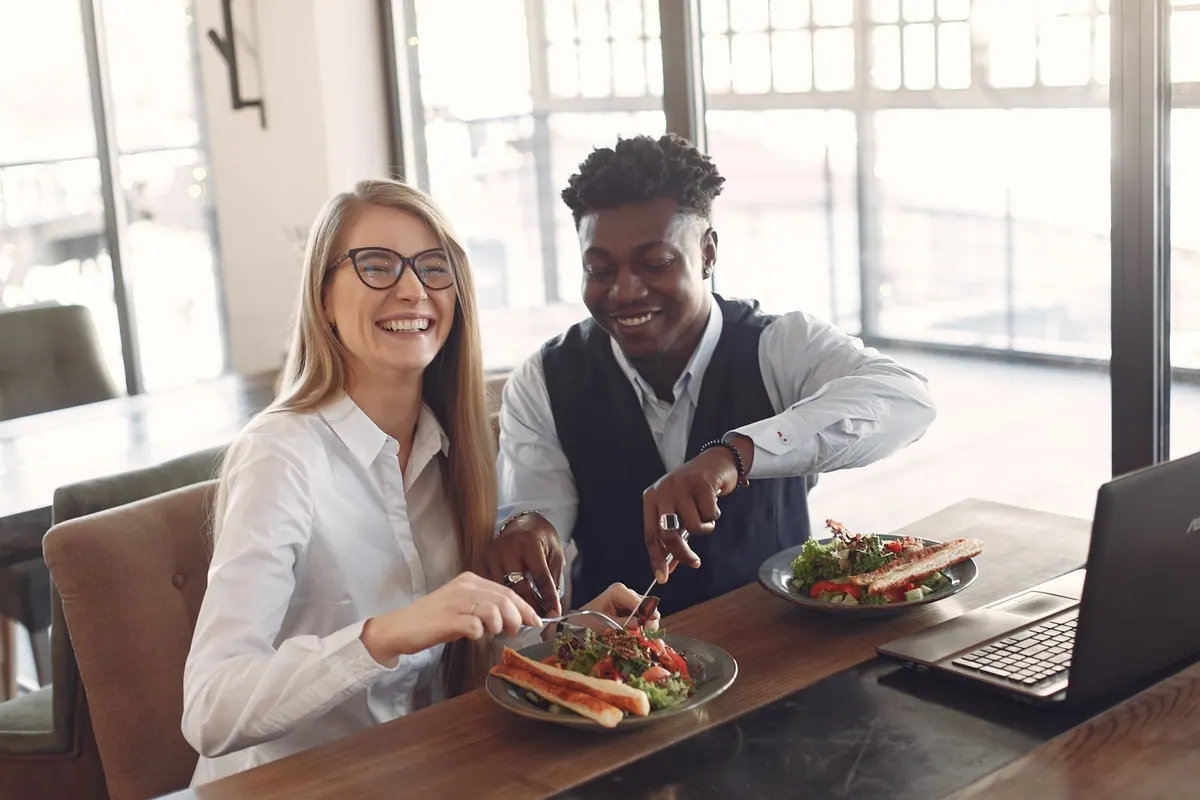 Colegas de trabalho diversos e sorridentes almoçando juntos em um café.