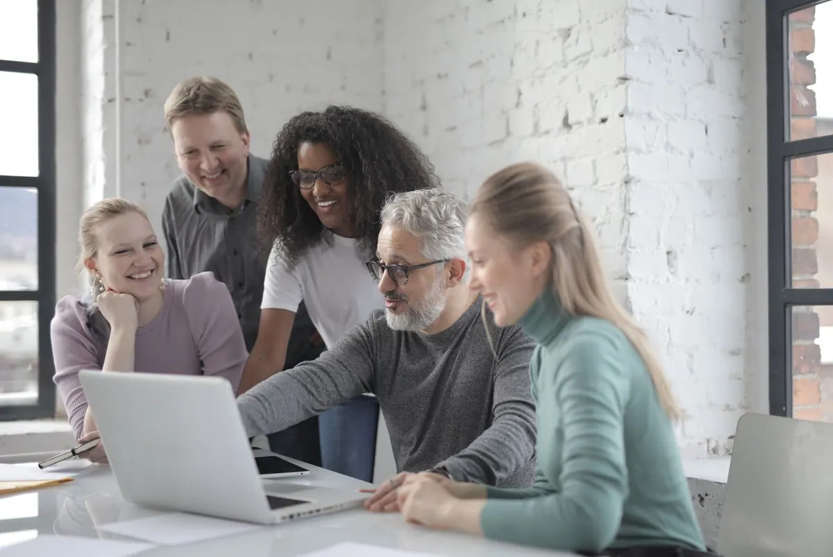 Grupo diverso de colegas sorrindo e discutindo um projeto no escritório.