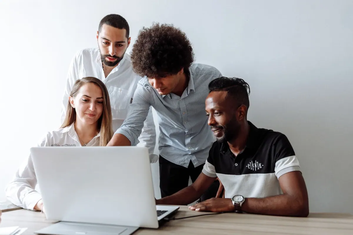Colegas de trabalho olhando para um laptop, discutindo opções de benefícios.