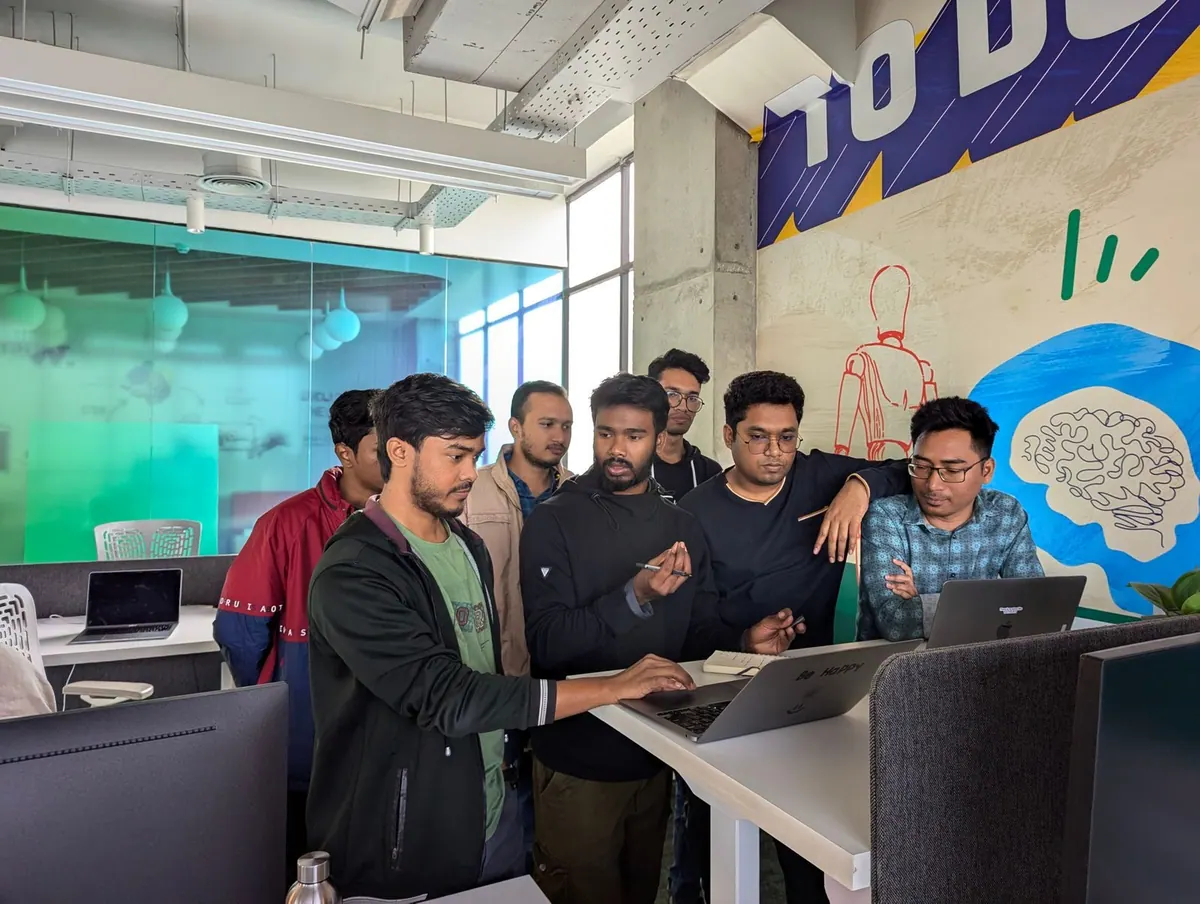 Equipe diversa colaborando em escritório moderno, focada em um laptop.