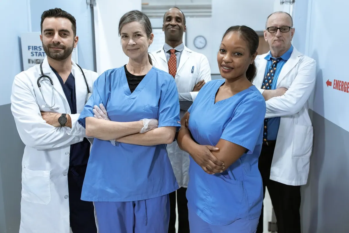 Equipe diversa de médicos e enfermeiros em um hospital, braços cruzados.