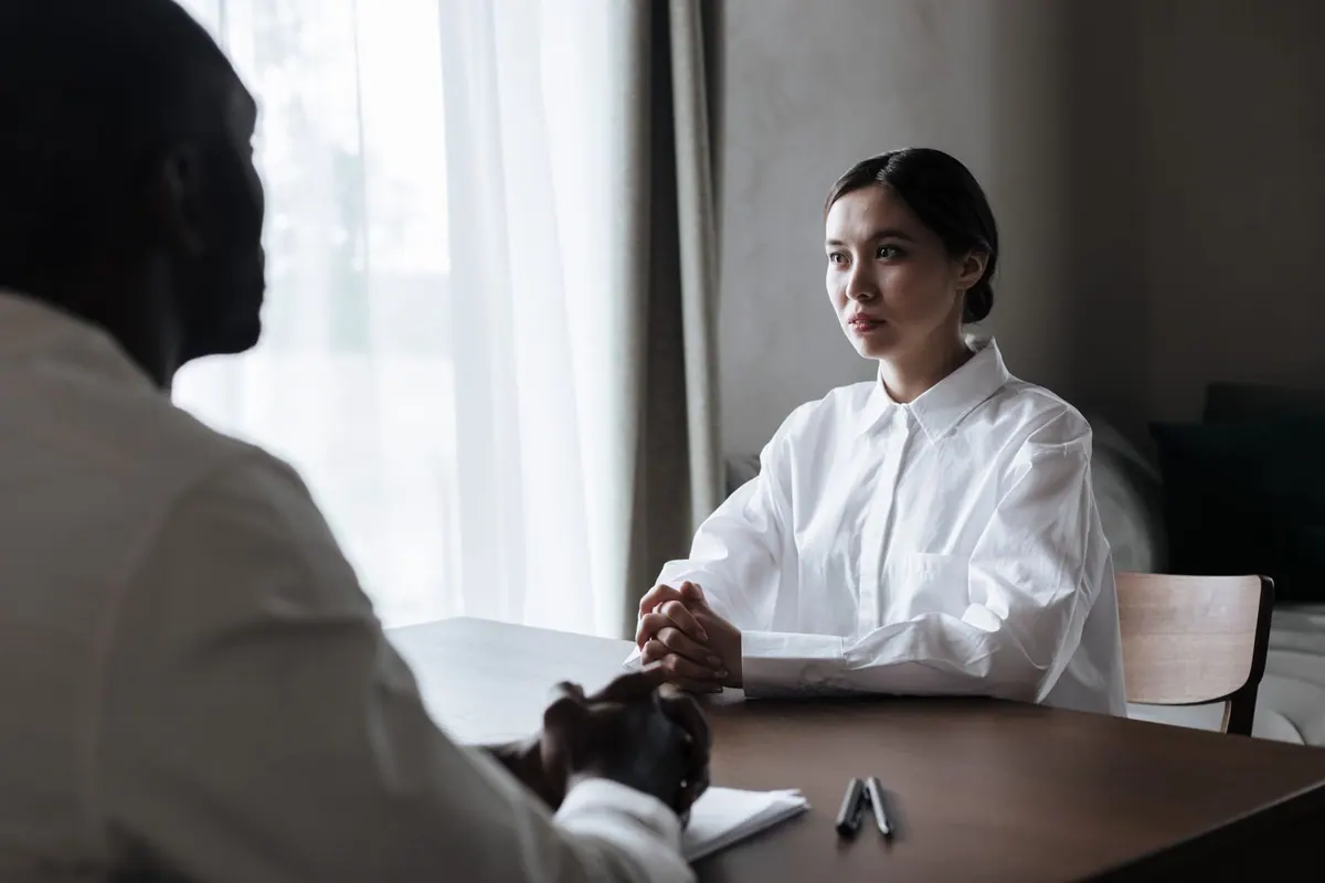 Duas pessoas em uma entrevista de emprego, uma de frente para a outra.