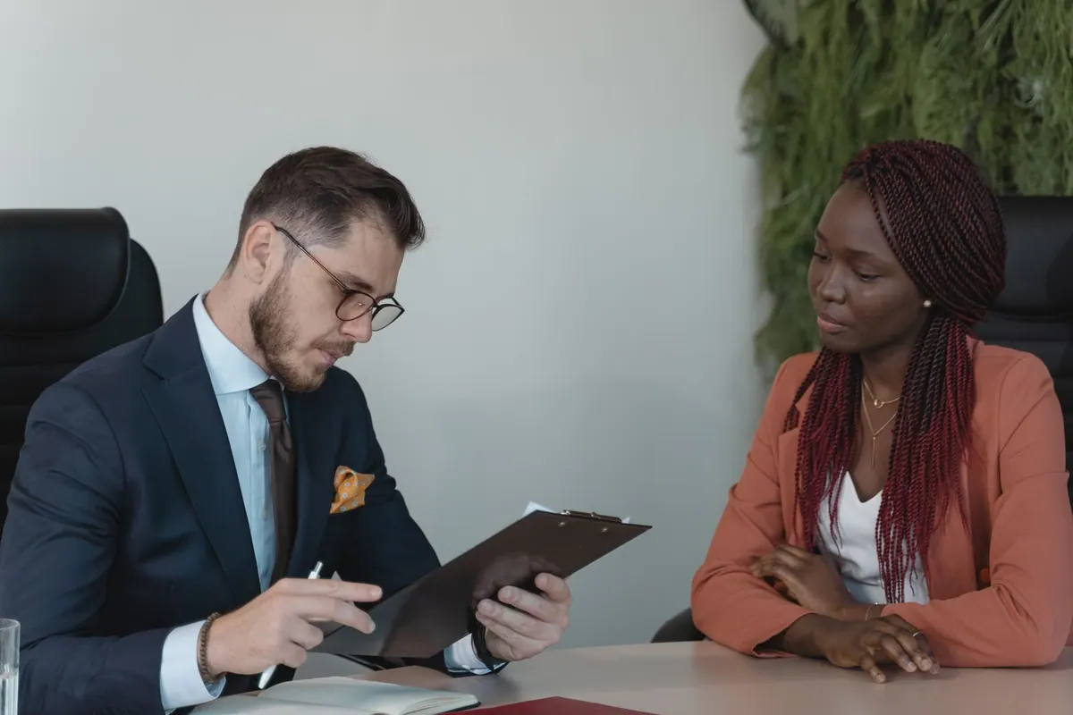 Entrevistador revisando currículo de candidata em processo de atração de talentos.