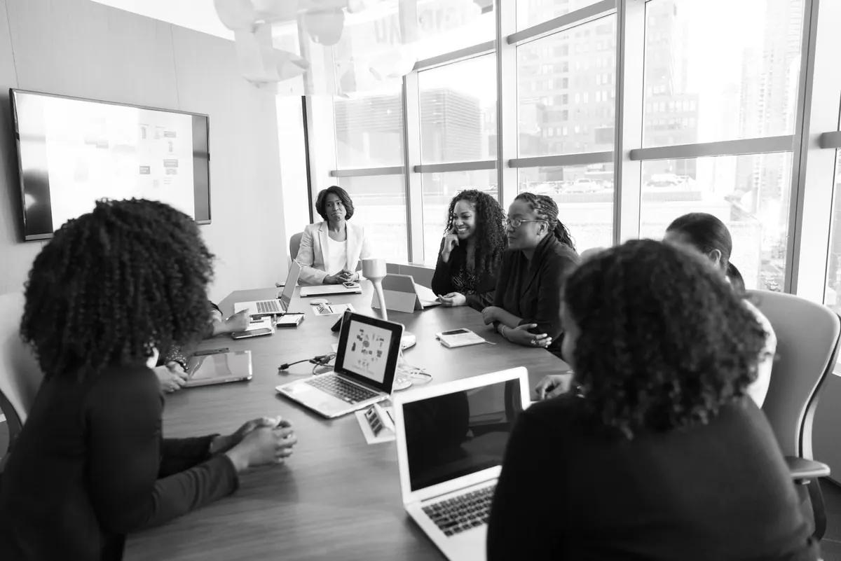 Mulheres negras em reunião de trabalho, discutindo e colaborando.