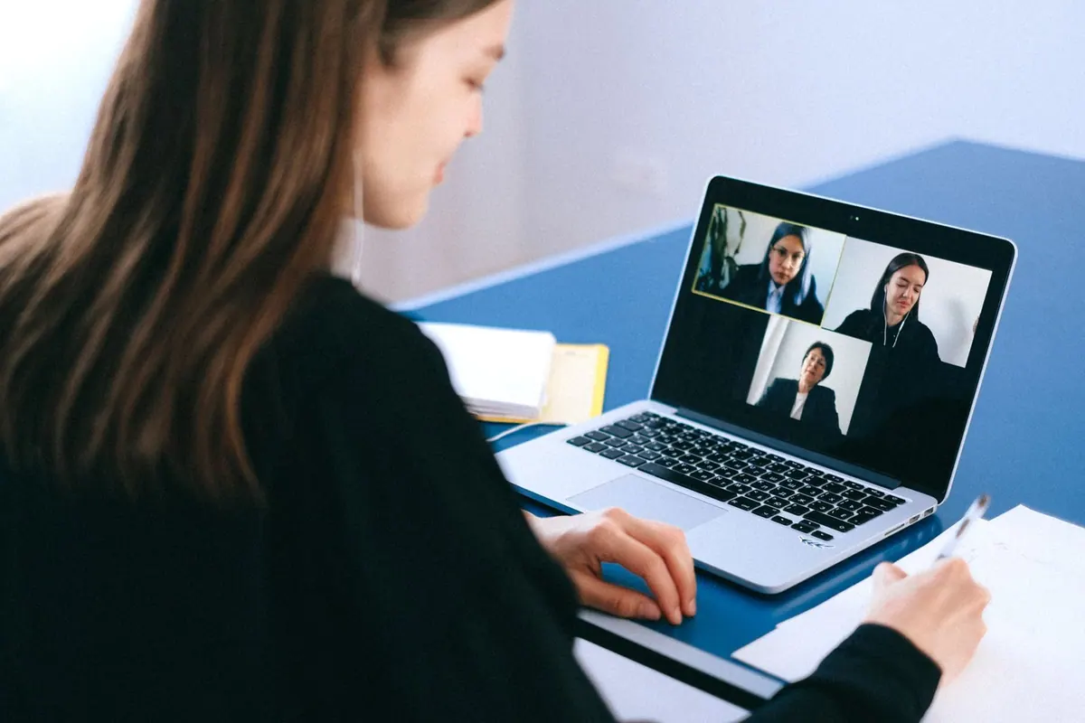 Mulher em videochamada com colegas de trabalho, simbolizando trabalho remoto.