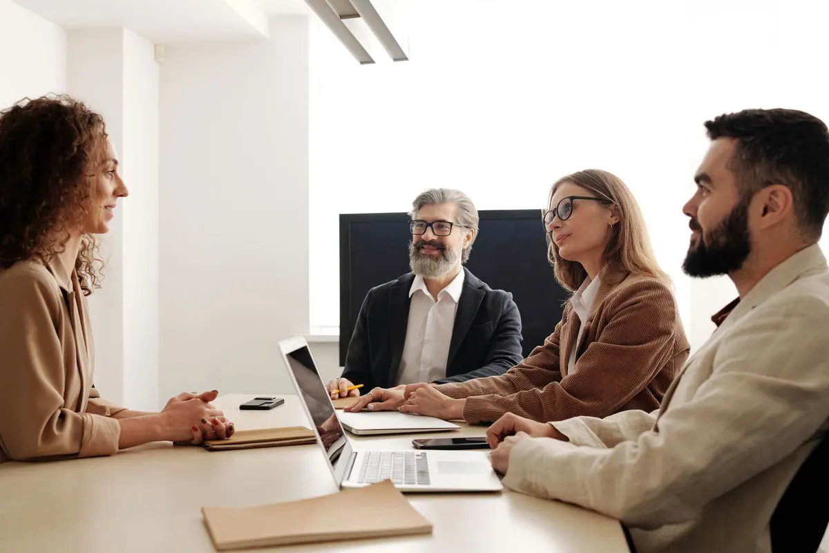 Entrevista de emprego com três gestores e uma candidata em uma sala de reunião.