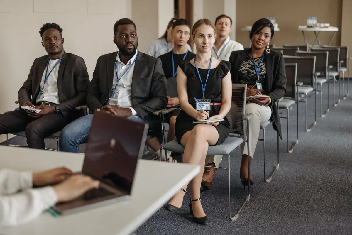 Pessoas diversas sentadas em cadeiras em uma sala de treinamento corporativo.