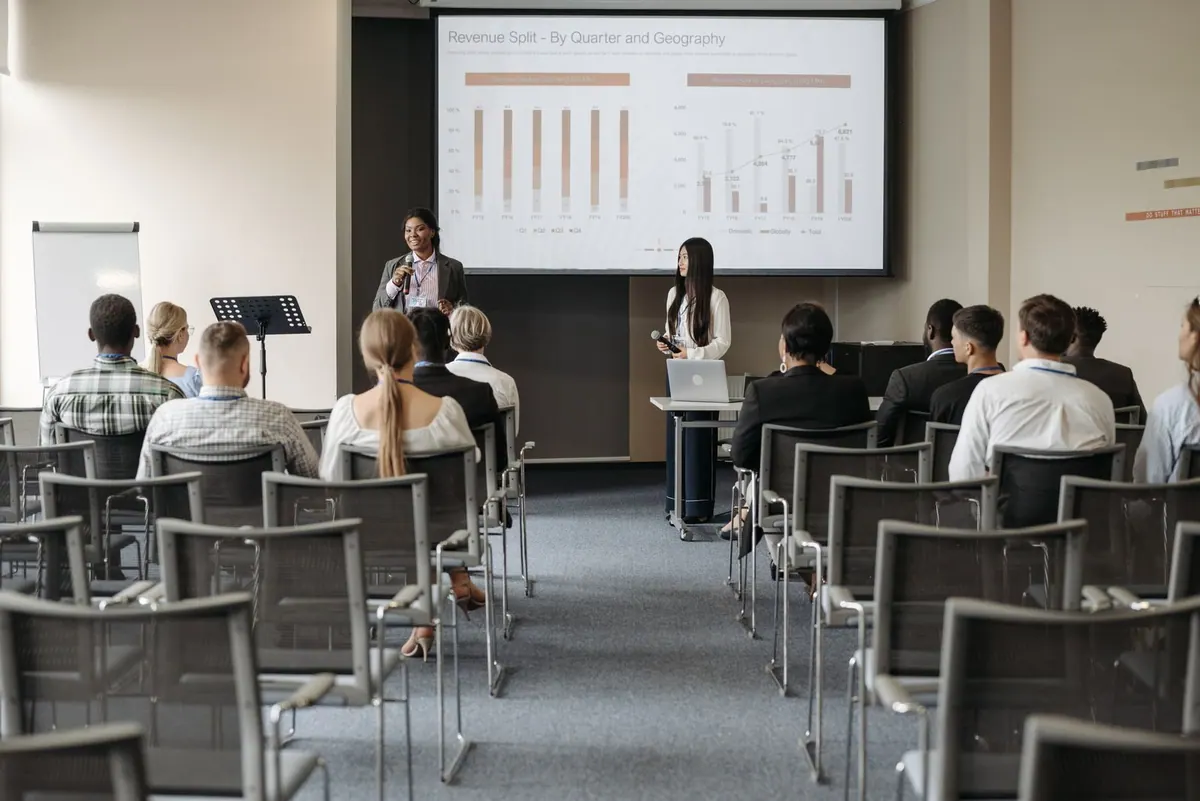 Profissionais em treinamento assistem a uma apresentação com gráficos em tela grande.