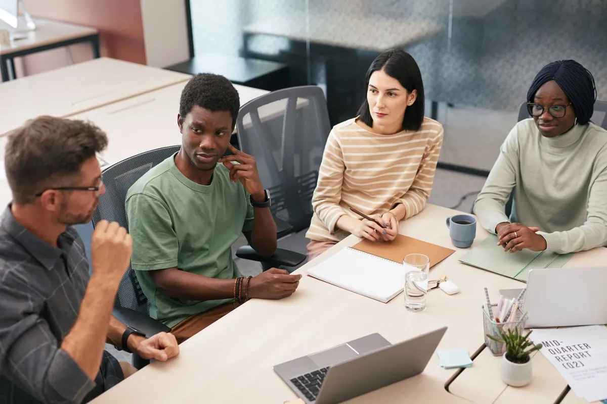 Pessoas diversas em uma reunião de trabalho, discutindo seriamente.