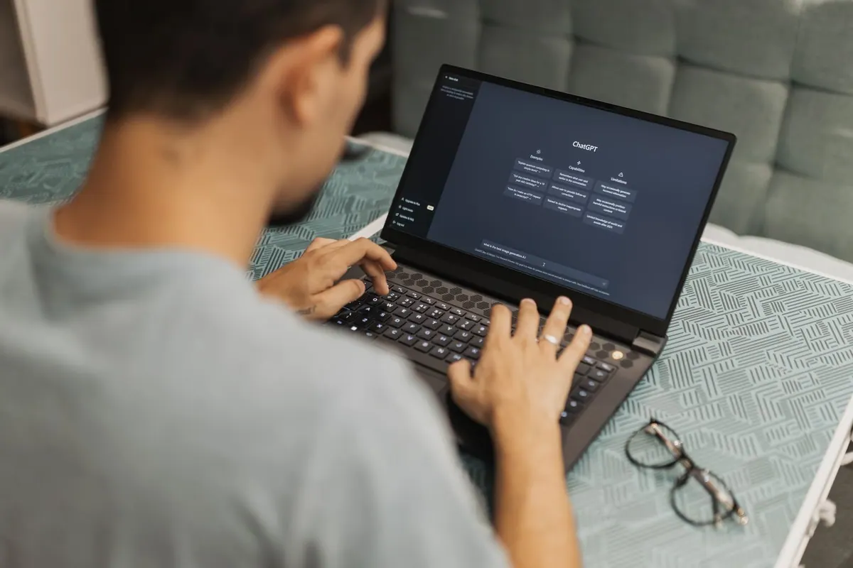 Homem usando laptop com interface de chatbot de inteligência artificial na tela.