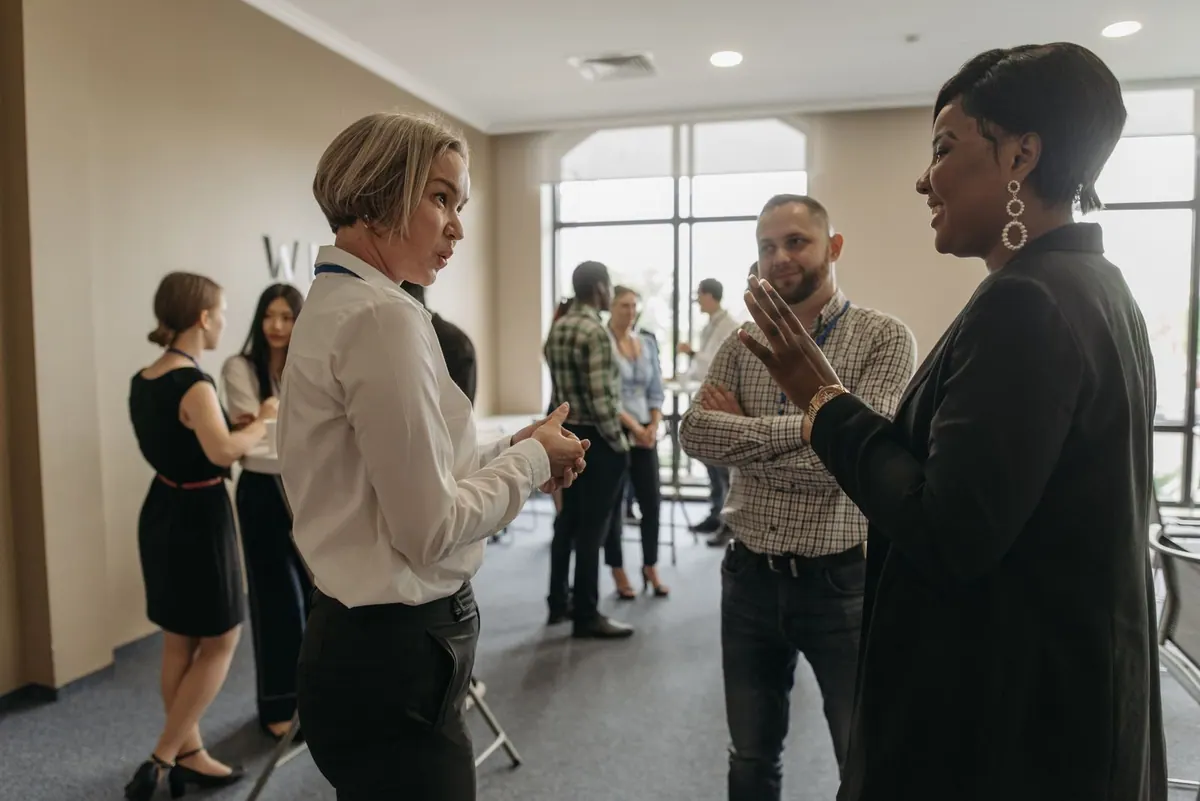Profissionais de RH conversando animadamente em um evento corporativo.