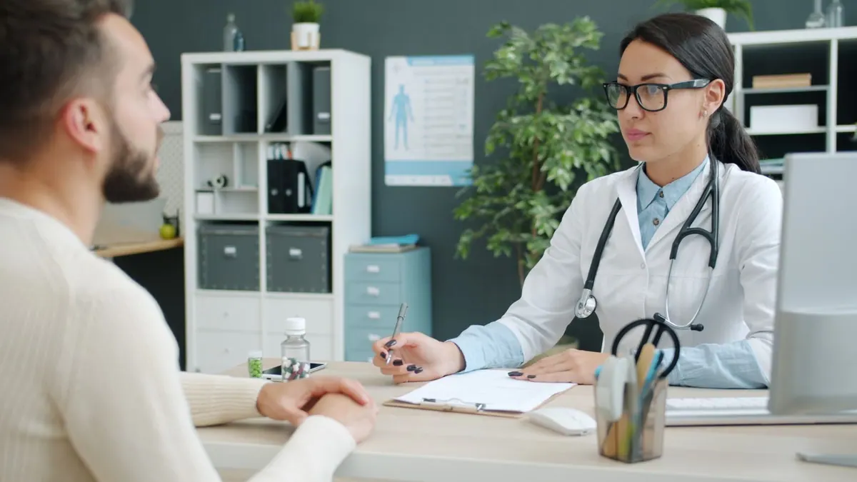 Médica atenta em consulta com paciente em consultório moderno.