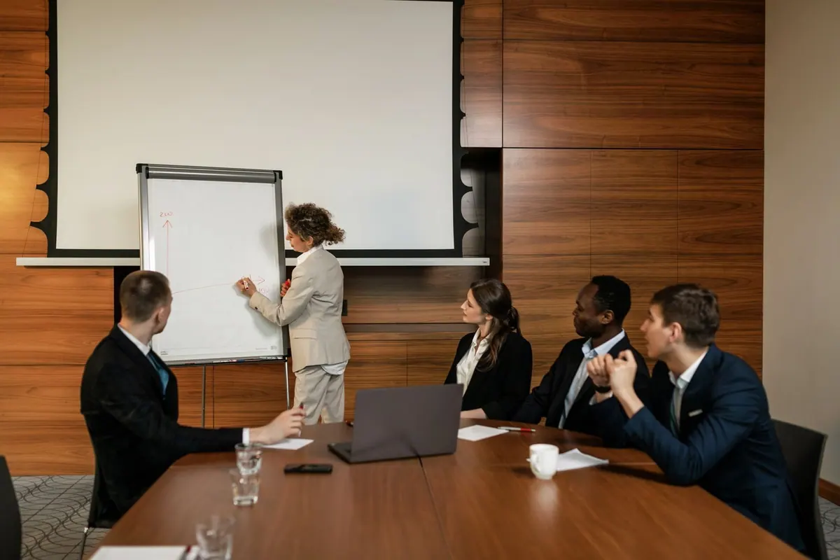 Pessoas de negócios em uma sala de reunião com uma mulher apresentando.