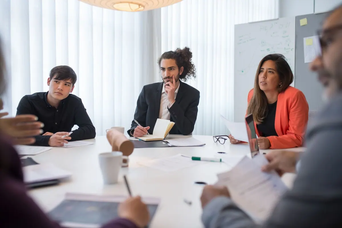 Pessoas em uma reunião de negócios, atentas à discussão.