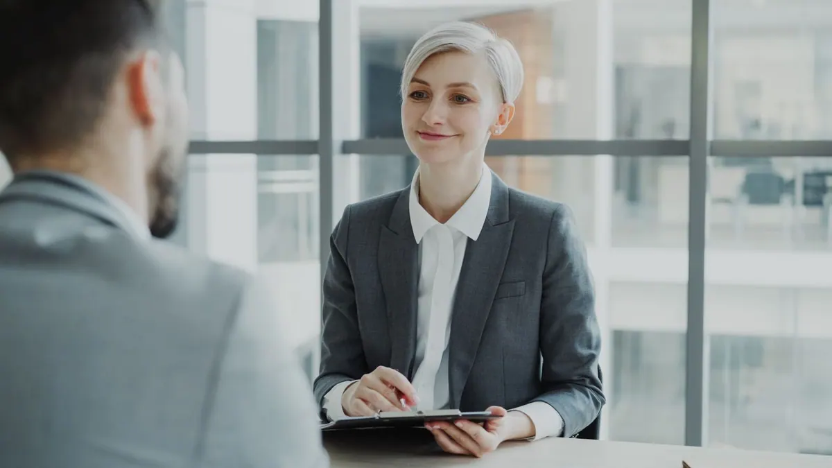 Entrevistadora sorridente e candidata em um escritório moderno durante uma entrevista de emprego.