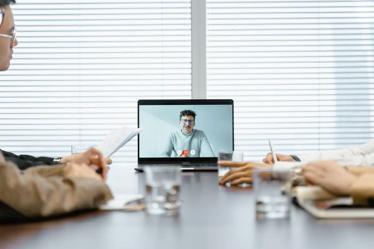 Pessoas em uma sala de reunião participando de uma entrevista virtual em um laptop.