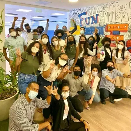Grupo diverso de pessoas sorrindo e fazendo gestos de paz e força.