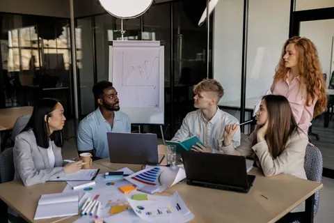 Grupo de profissionais diversos em reunião de trabalho, discutindo ideias e projetos.