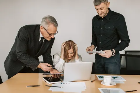 Mulher estressada em reunião de trabalho com dois colegas de escritório.