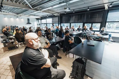 Pessoas sentadas em uma sala de reunião, atentas a uma apresentação ou palestra.