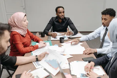 Reunião de negócios com pessoas de diversas etnias e culturas, discutindo documentos.