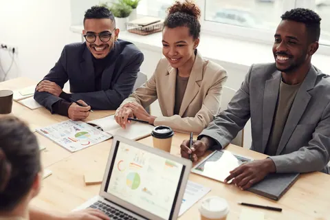 Pessoas sorrindo em uma reunião de trabalho, transmitindo um ambiente saudável.