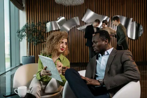 Dois colegas de trabalho discutindo documentos em um ambiente de escritório moderno.