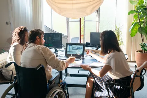 Colegas diversos trabalhando juntos, incluindo pessoa em cadeira de rodas.