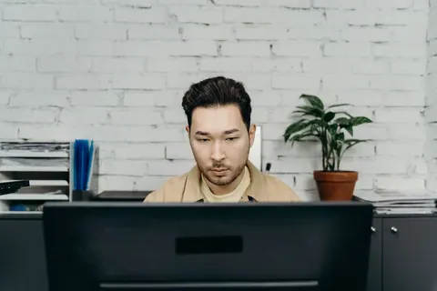 Homem focado trabalhando em um computador em um escritório moderno.