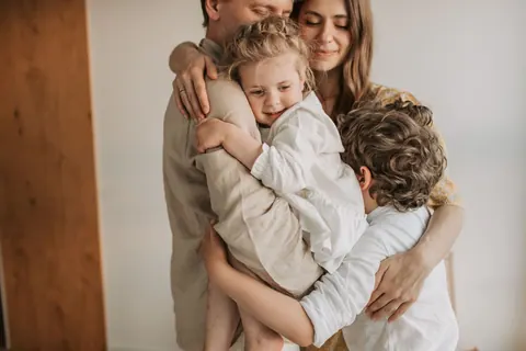 Família abraçada, pais e filhos, transmitindo carinho e união.