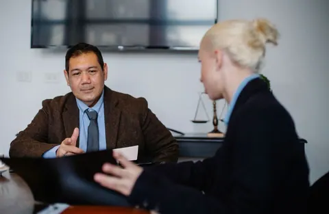 Dois colegas de trabalho multiétnicos concentrados discutindo negócios em um escritório.