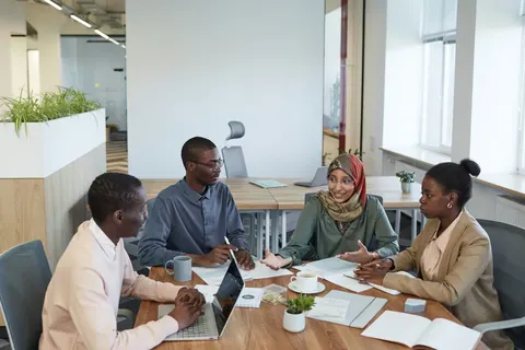 Pessoas diversas em uma reunião de escritório, discutindo e colaborando.