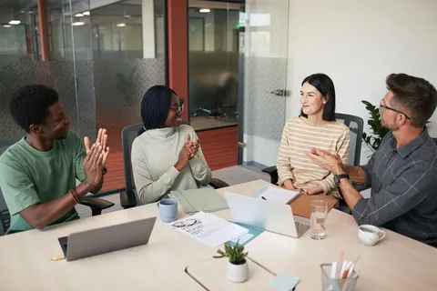 Grupo de pessoas diversas em uma reunião de trabalho, conversando e interagindo.