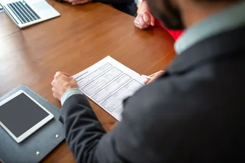 Homem lendo um formulário de candidatura em uma mesa de escritório.