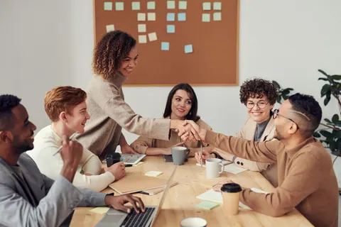Colegas de trabalho de diversas etnias apertam as mãos em uma reunião colaborativa.