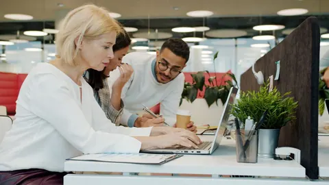 Equipe diversa e intergeracional colaborando em escritório moderno.