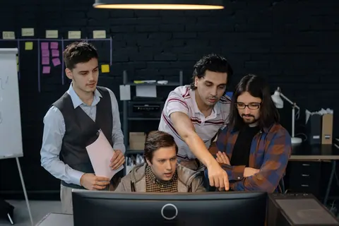 Equipe de trabalho colaborando em frente a um computador em um escritório.