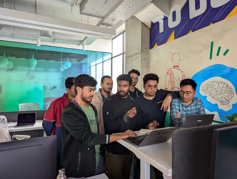 Equipe diversa colaborando em escritório moderno, focada em um laptop.