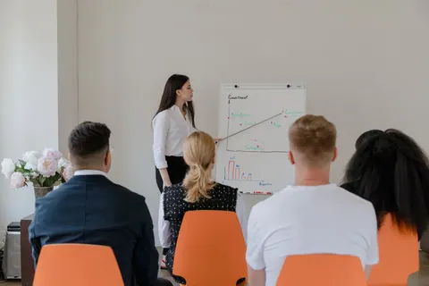 Mulher de negócios apresentando um gráfico de desempenho para colegas em reunião.